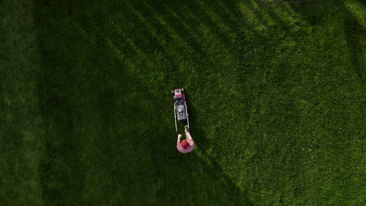 Aerial View Of Gardener Mowing A Lush Green Lawn