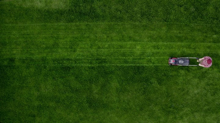 Aerial View Of Gardener Mowing Lush Green Lawn