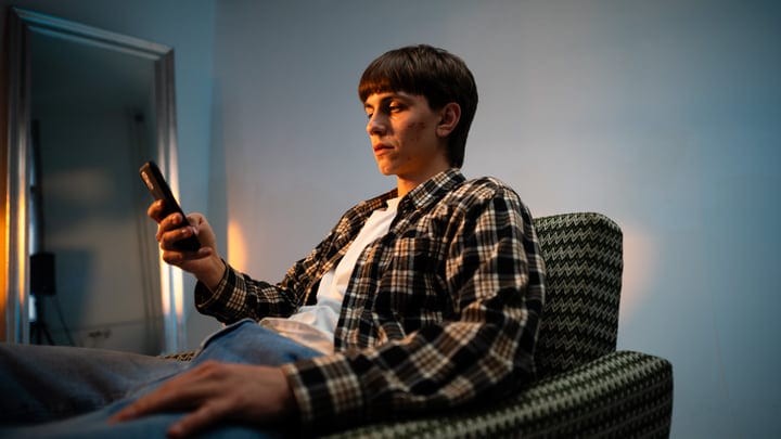 Young Adult Engages with Smartphone in Cozy Studio Setting
