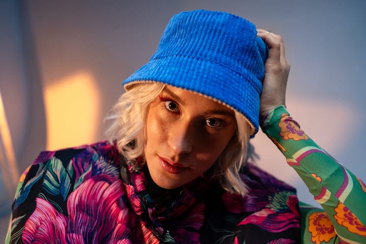Vibrant Style Meets Curiosity Under A Blue Hat