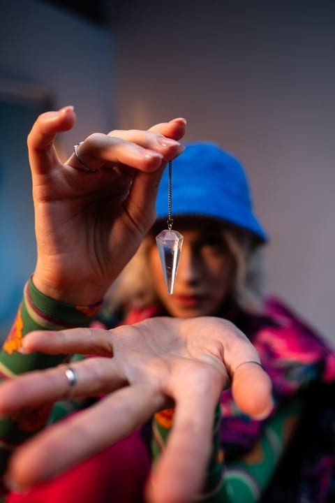 Gen Z Hand Holds Crystal Pendant Against Studio Light