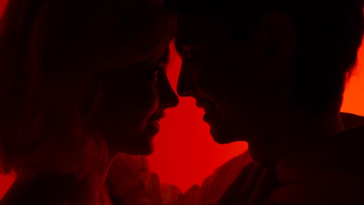 Silhouettes Share A Whisper Under Crimson Light