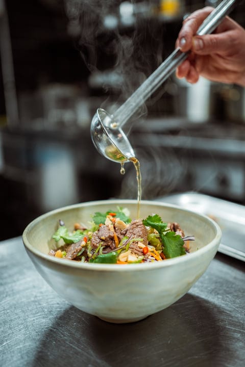 A Chef Drizzles Flavor Over A Vibrant Salad Bowl