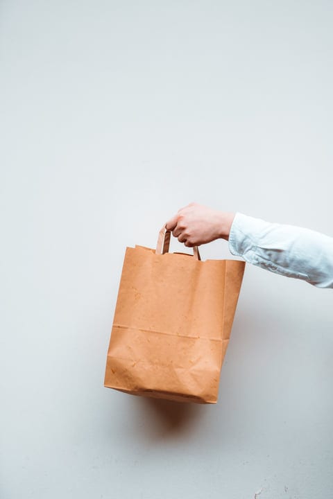 Hand Holding Eco-Friendly Paper Bag Against White Background