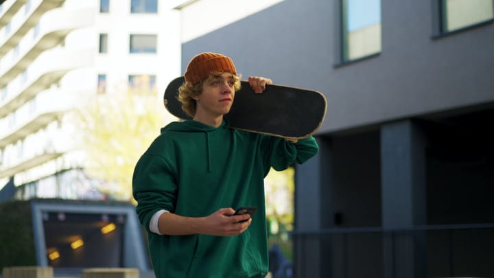 Youth Embraces Urban Energy With Skateboard And Smartphone