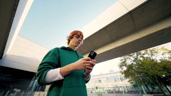 Young Urbanite Checks His Phone Under City Bridge