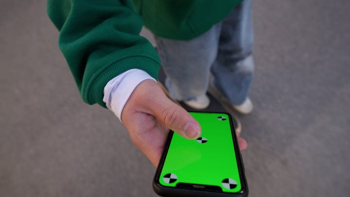 Young Hand Engages with Smartphone Under Neon Lights