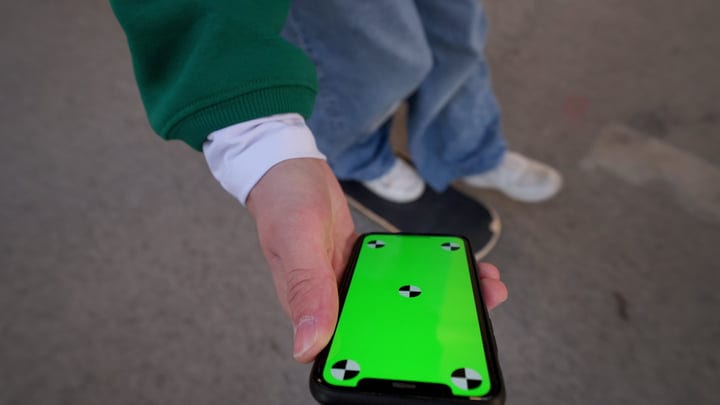Hand Holding Smartphone With Vibrant Green Screen Display