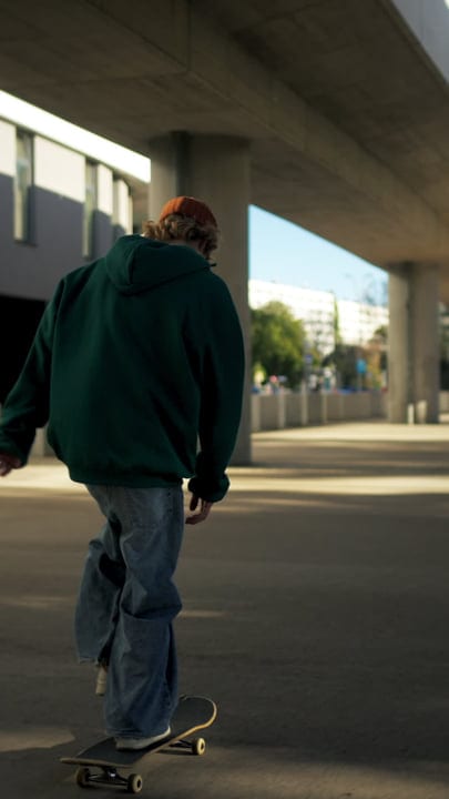 Skater Glides Effortlessly Underneath Urban Overpass At Dusk