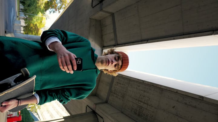 Urban Skater Embraces Technology Under City Bridge
