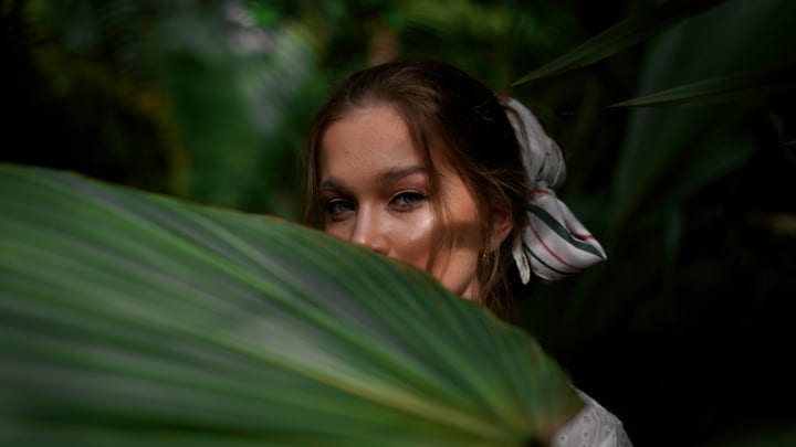 A Woman's Eyes Peek Through Lush Tropical Leaves
