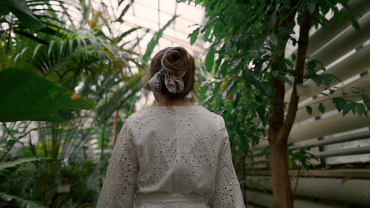 A Woman Wanders Through Lush Greenery In A Tropical Oasis