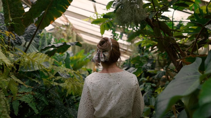 A Woman Immersed In Tropical Greenhouse Serenity