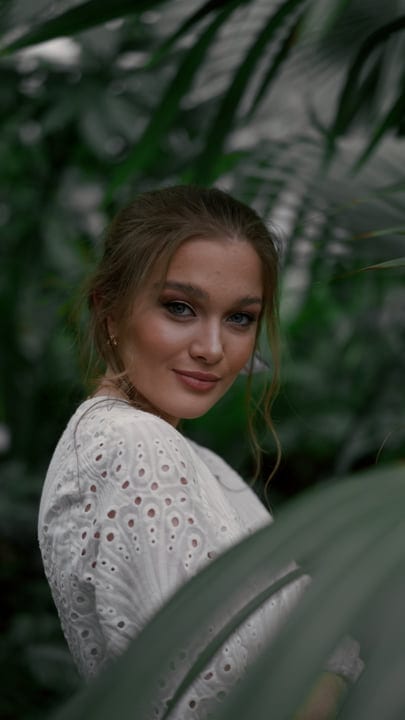 A Woman's Gentle Smile Amidst Lush Greenery