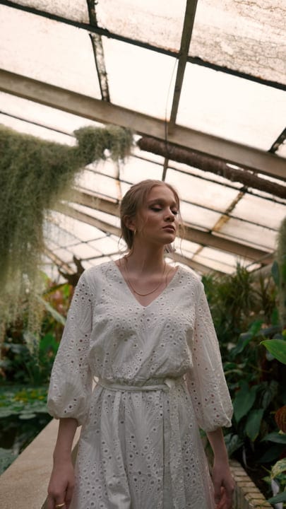 Serene Woman Strolling Through Lush Tropical Greenhouse