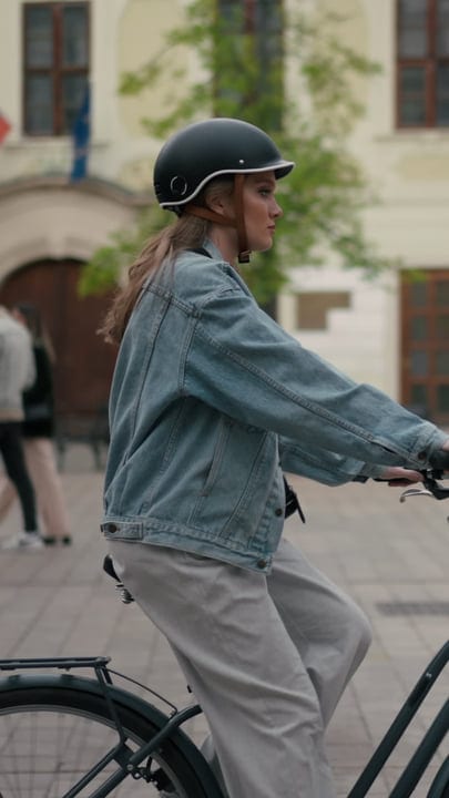 Woman in Denim Jacket Cycling Through Urban Square