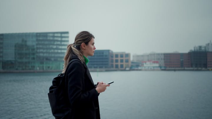 Businesswoman Pauses By Copenhagen Waterfront With Smartphone