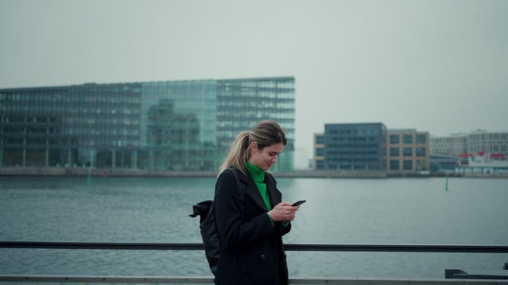 Focused Businesswoman Checks Phone By Copenhagen Waterfront