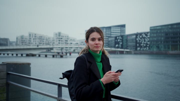Businesswoman With Phone Strolls Along Copenhagen Waterfront