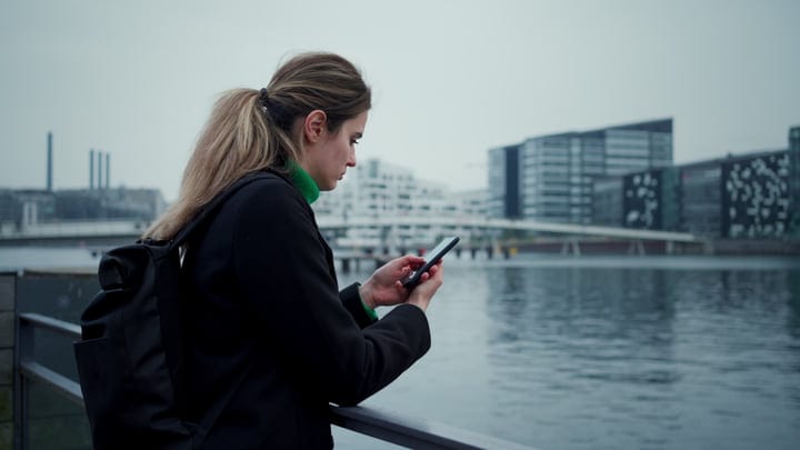Businesswoman Checks Phone By Copenhagen Waterfront