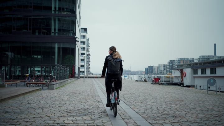Confident Businesswoman Cycling Through Copenhagen's Modern Streets