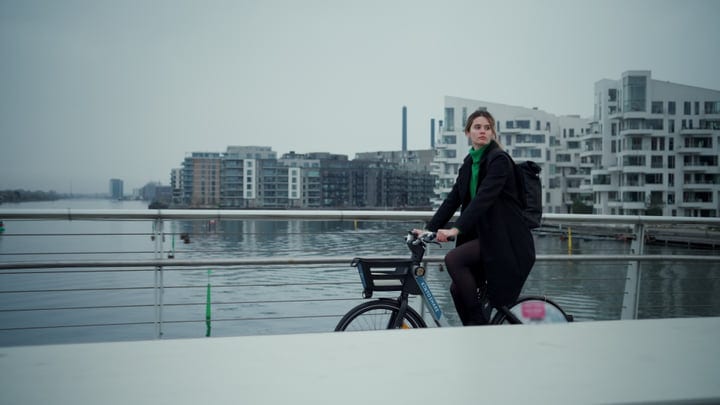 Businesswoman Cycling Along Copenhagen's Waterfront Skyline