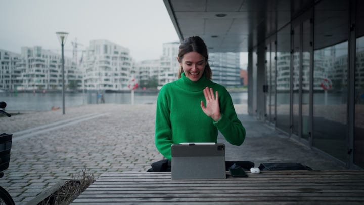 Businesswoman Waves Warmly During Virtual Meeting Outdoors