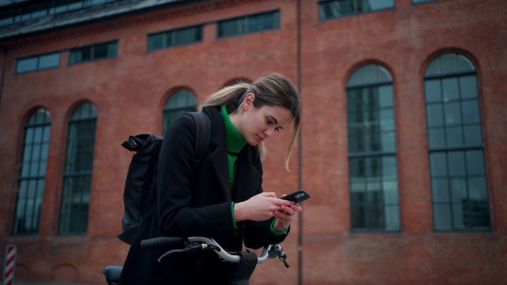 Focused Businesswoman Checks Her Phone While Cycling in Copenhagen