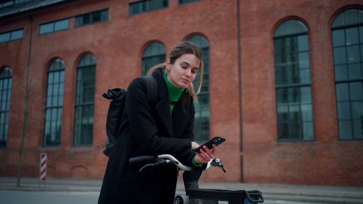 Confident Businesswoman Checks Phone While Cycling In Copenhagen