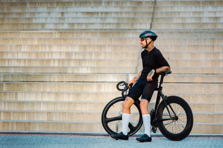 Tattooed Cyclist Pauses Against Urban Steps At Dusk