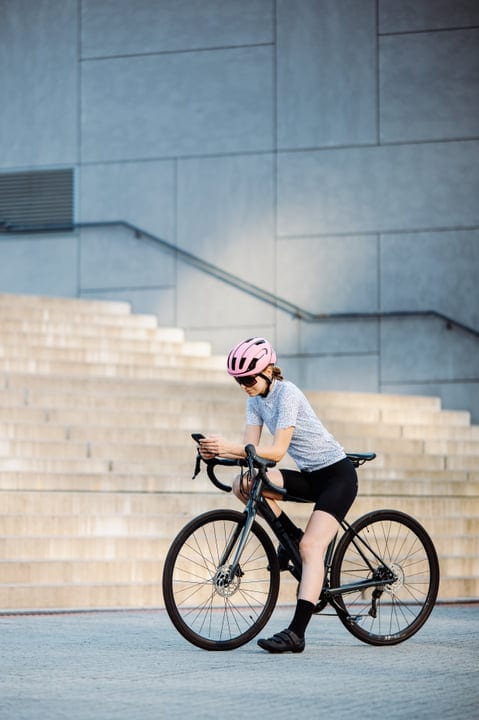 Cyclist Pauses to Check Her Phone in Urban Setting