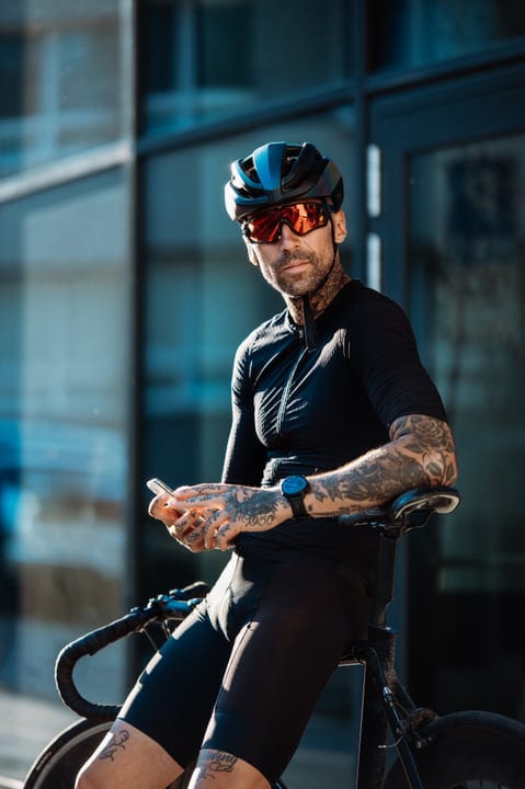 Tattooed Cyclist Pauses to Check His Phone in City