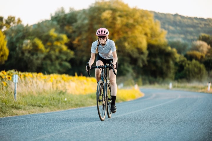 Solo Cyclist Pedals Through Sunlit Countryside Road
