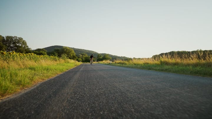 Cyclist Embraces Open Road Amidst Rolling Hills