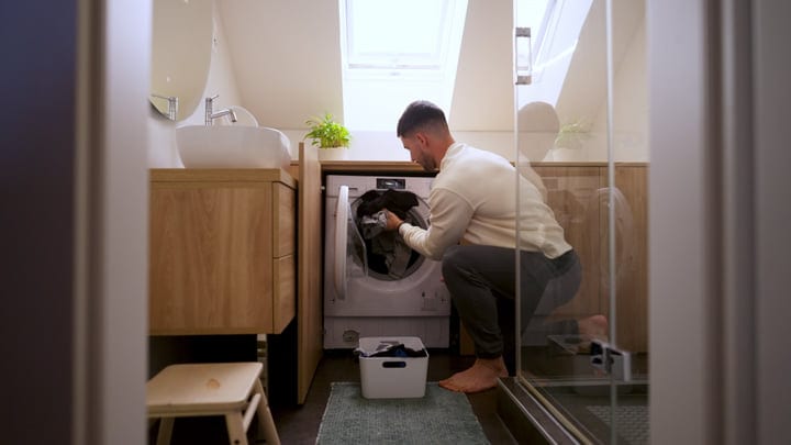 Barefoot Man Juggles Laundry and Work at Home