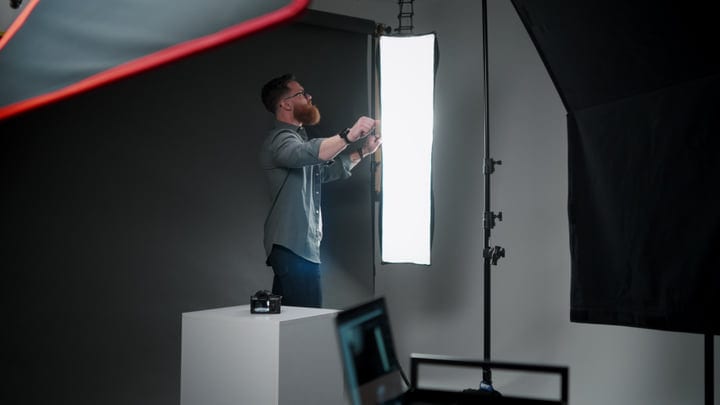 Photographer Adjusts Lighting Equipment In Studio Environment