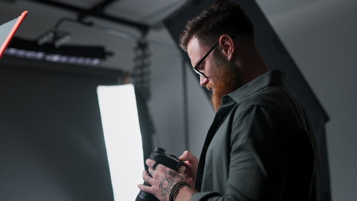Focused Photographer Adjusting Camera in Modern Studio