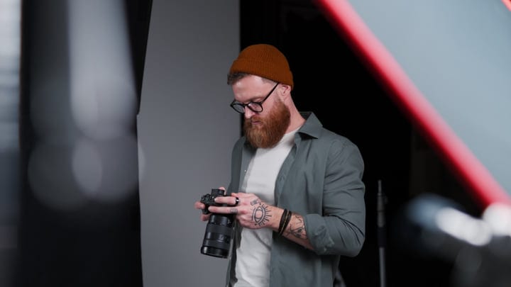 Focused Photographer Adjusts Camera Settings in Studio Light