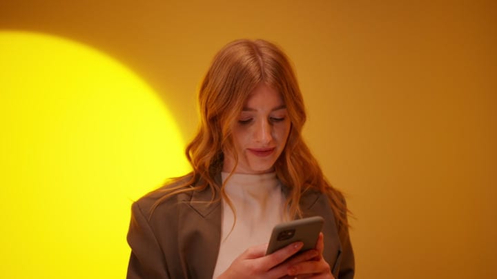 Young Woman Engages with Her Smartphone in Warm Light