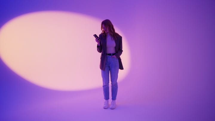 Young Woman Engages With Smartphone In Vibrant Studio Light