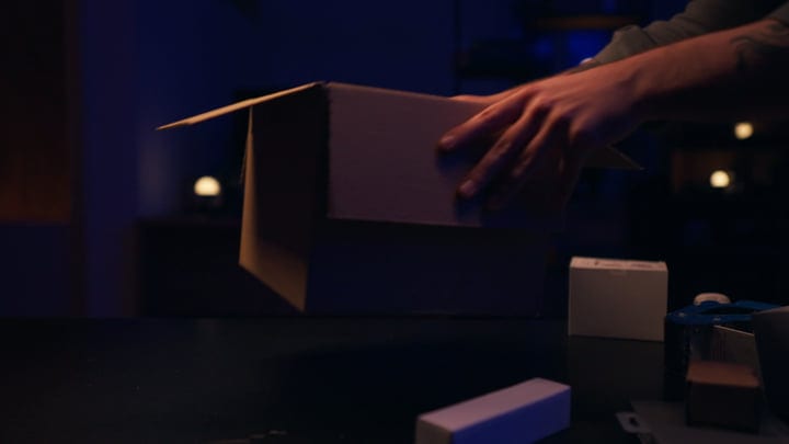 Hands Gently Unpacking Boxes In Studio Shadows