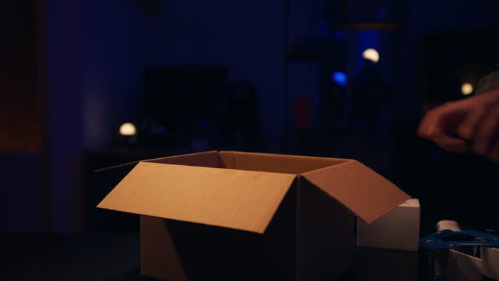 Hands Prepare Cardboard Box Under Studio Lights