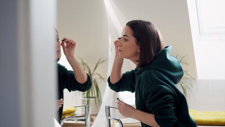 Morning Rituals: Woman Applying Makeup in Bright Bathroom