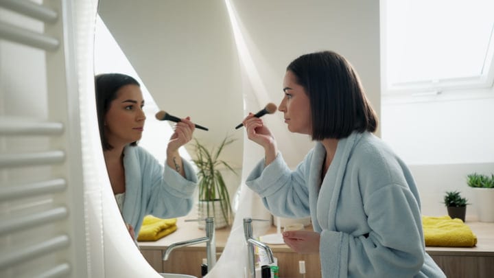 Morning Rituals: Woman Perfects Her Makeup In The Mirror