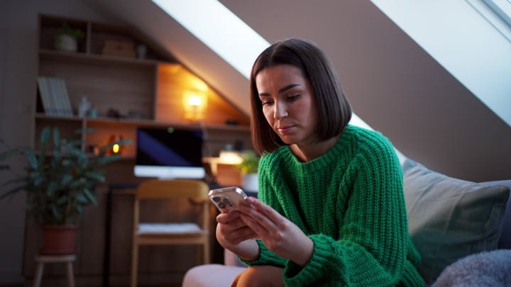 Young Woman Engages With Her Phone In Cozy Attic Space