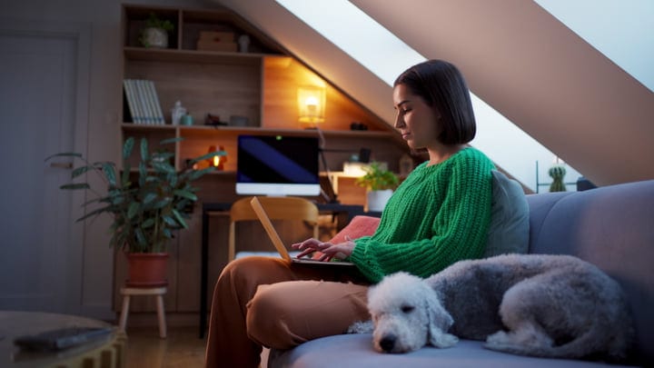 Woman Typing on Laptop Beside Her Sleeping Dog at Home