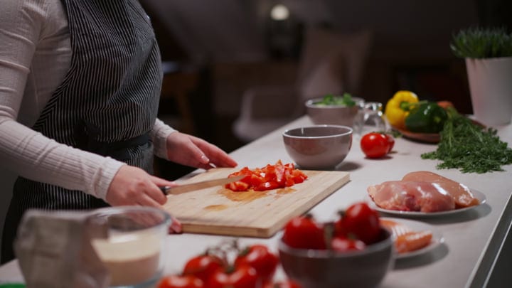 A Home Cook Dices Fresh Tomatoes In Her Kitchen