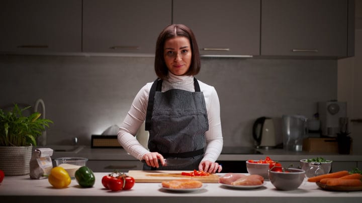 A Woman Embraces Culinary Creativity In Her Kitchen
