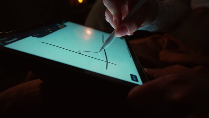 A Hand Sketches Ideas on a Tablet in Cozy Evening Light