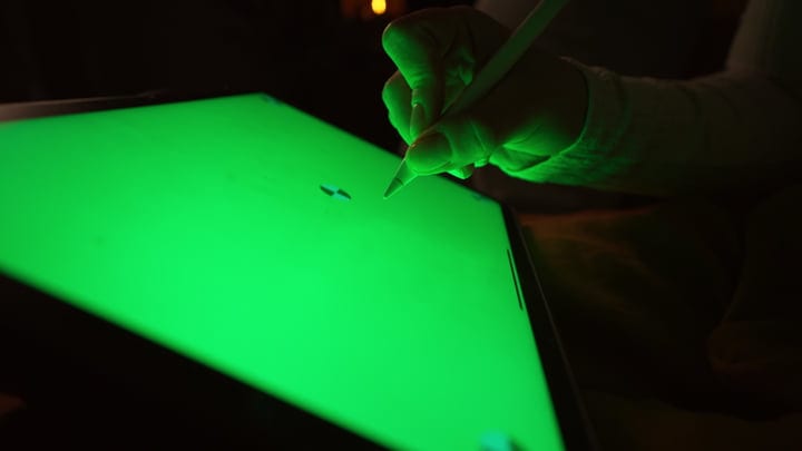 Illuminated Creativity: Woman Sketching On Digital Tablet